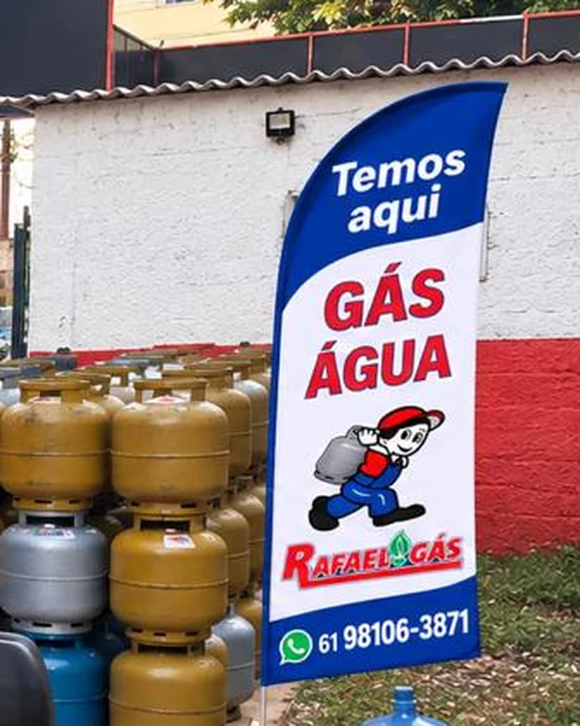Bandeira da loja anunciando gás e água, ao lado dos botijões e de um galão de 20 litros